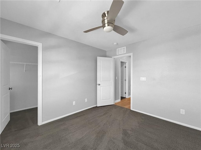 unfurnished bedroom with carpet, baseboards, visible vents, a closet, and a walk in closet