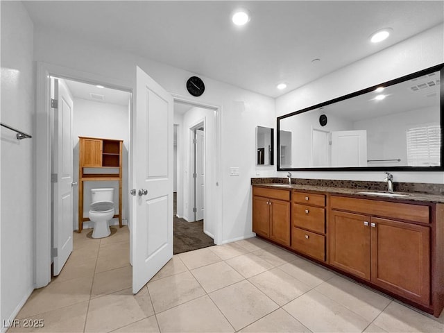 bathroom featuring double vanity, recessed lighting, toilet, and a sink