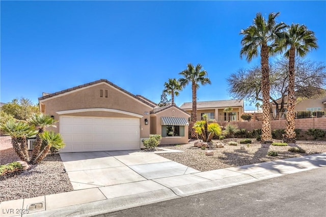 view of front of house featuring stucco siding, driveway, an attached garage, and fence