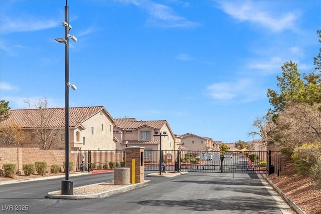 view of street with street lighting, a gated entry, a residential view, curbs, and a gate