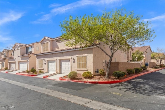 view of front of house featuring a tiled roof, a residential view, driveway, and stucco siding