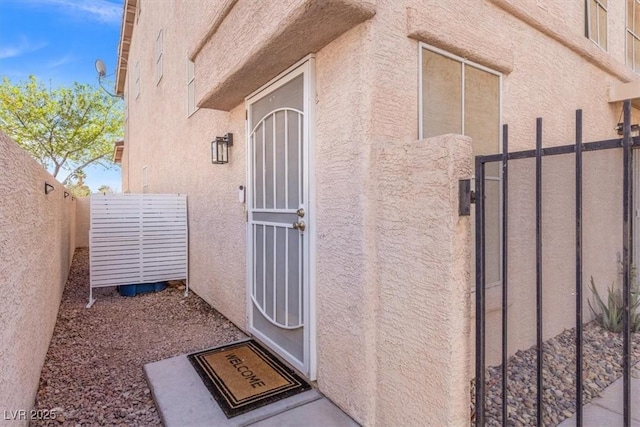 doorway to property with fence and stucco siding