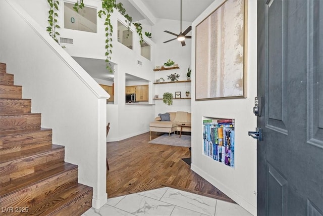 entryway with beam ceiling, marble finish floor, a ceiling fan, stairway, and baseboards