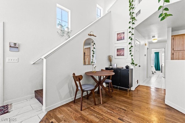 interior space featuring arched walkways, stairway, light wood-type flooring, and baseboards