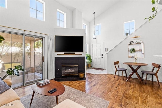 living room featuring a tile fireplace, baseboards, and wood finished floors