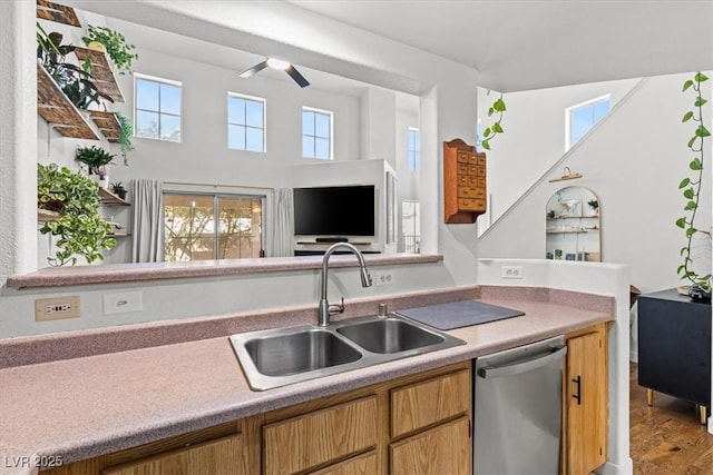 kitchen featuring light countertops, stainless steel dishwasher, wood finished floors, a ceiling fan, and a sink