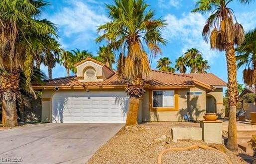 view of front of home with concrete driveway, a tiled roof, an attached garage, and stucco siding