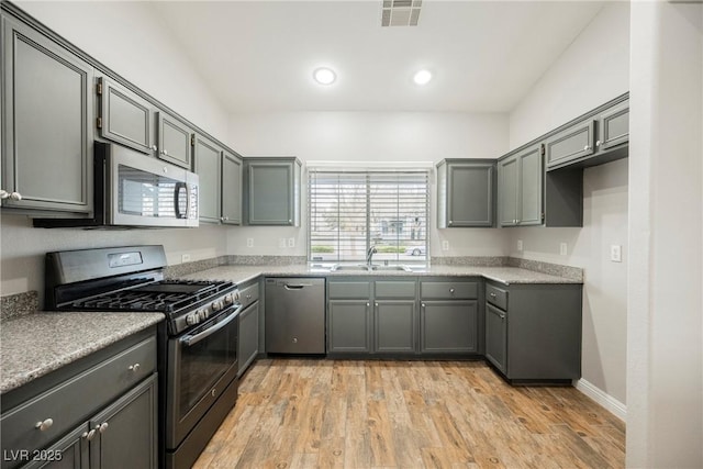 kitchen featuring visible vents, light countertops, light wood-style flooring, appliances with stainless steel finishes, and a sink