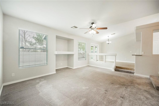 unfurnished living room with visible vents, ceiling fan with notable chandelier, baseboards, carpet flooring, and lofted ceiling