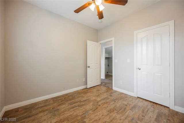 unfurnished bedroom with a ceiling fan, baseboards, and wood finished floors