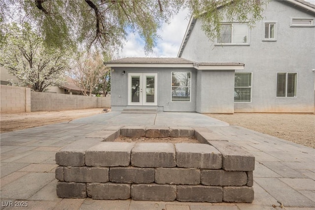 rear view of house with french doors, a patio, stucco siding, and fence