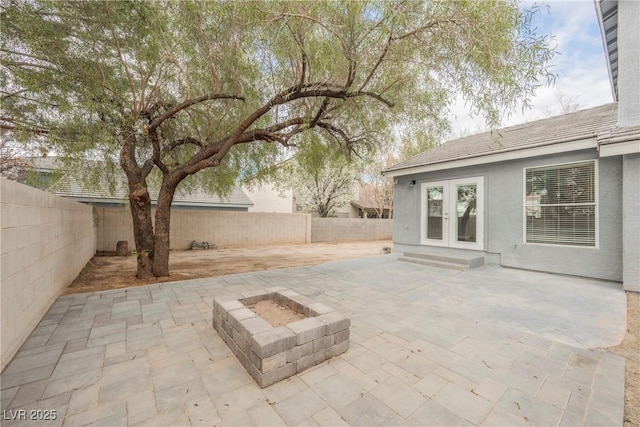 view of patio / terrace with a fenced backyard, french doors, a fire pit, and entry steps