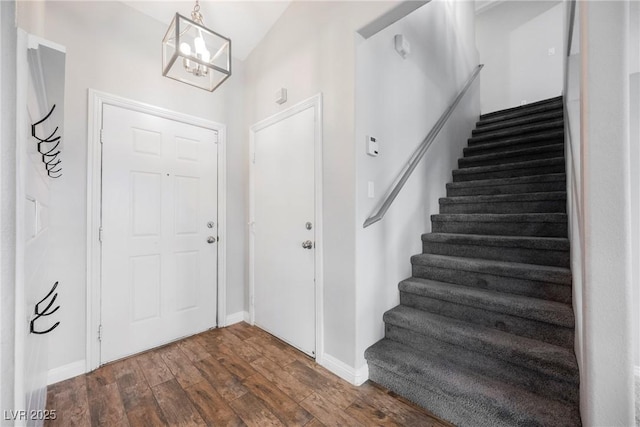 entrance foyer with an inviting chandelier, stairway, dark wood-style floors, and baseboards