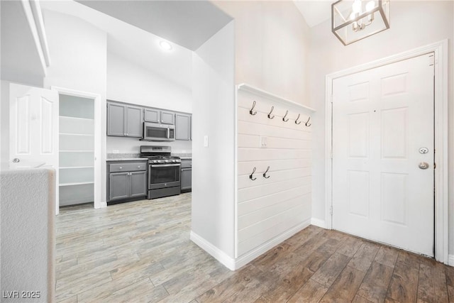 interior space featuring a notable chandelier, baseboards, light wood-type flooring, and high vaulted ceiling