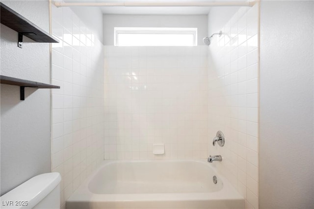 full bath featuring toilet, a textured wall, and washtub / shower combination