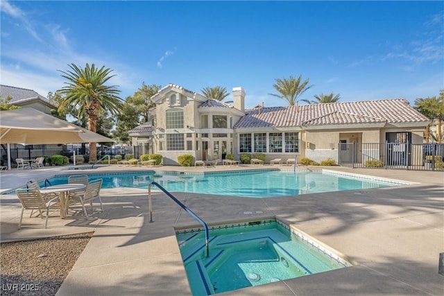 pool with a patio area, a community hot tub, and fence