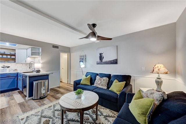 living area with visible vents, a ceiling fan, and light wood finished floors