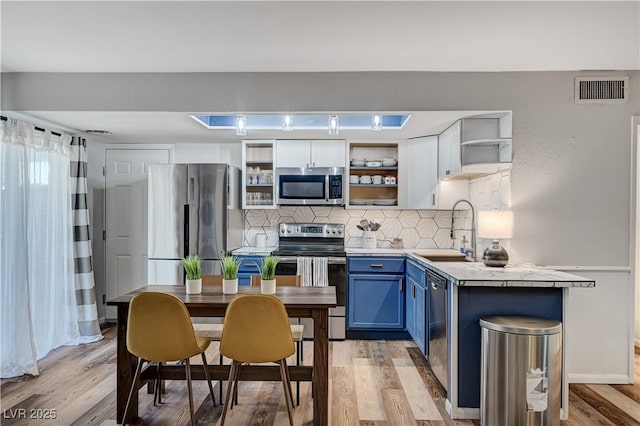 kitchen with visible vents, open shelves, a sink, stainless steel appliances, and blue cabinets