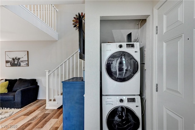 laundry area with wood finished floors, laundry area, and stacked washing maching and dryer