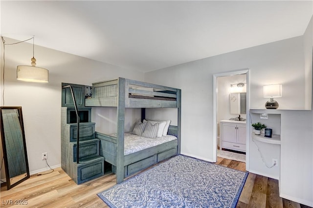 bedroom featuring connected bathroom, baseboards, and wood finished floors