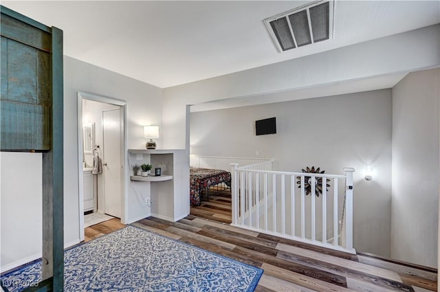 corridor featuring visible vents, an upstairs landing, and wood finished floors