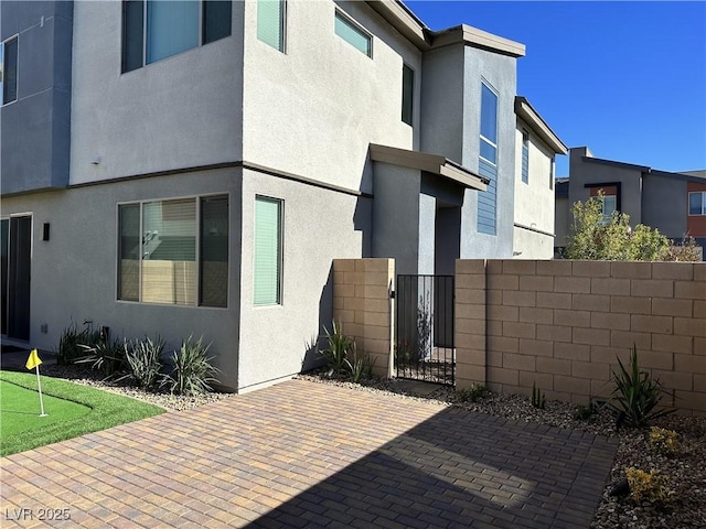 exterior space with stucco siding, fence, and a gate