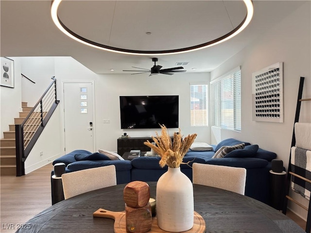 living room with visible vents, wood finished floors, a ceiling fan, and stairway