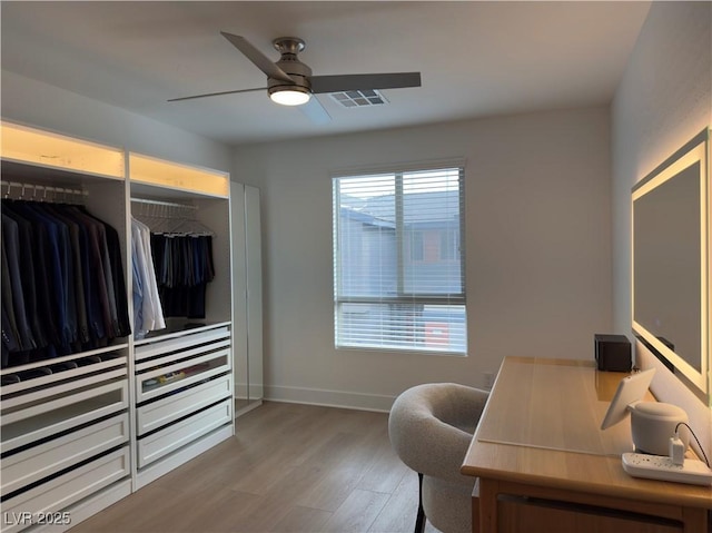 home office with a ceiling fan, visible vents, wood finished floors, and baseboards