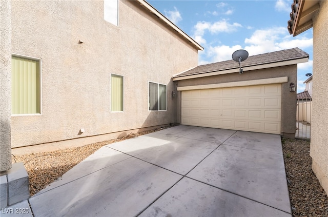 view of property exterior with a tile roof, concrete driveway, a garage, and stucco siding