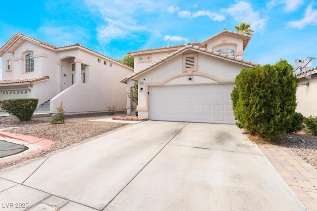 mediterranean / spanish house with a tile roof, a garage, driveway, and stucco siding