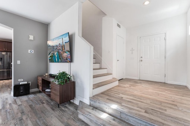 entrance foyer with visible vents, baseboards, light wood-style flooring, and stairs