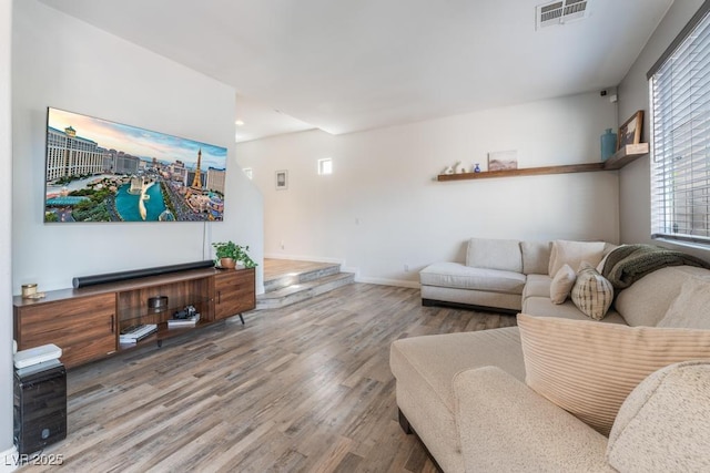 living area featuring visible vents, baseboards, and wood finished floors