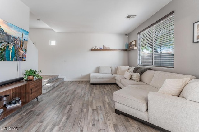 living area featuring visible vents, stairway, wood finished floors, and baseboards