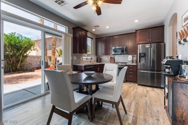 kitchen with visible vents, backsplash, stainless steel appliances, light wood-style floors, and dark brown cabinetry