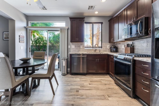 kitchen with light wood finished floors, visible vents, dark brown cabinetry, appliances with stainless steel finishes, and a sink