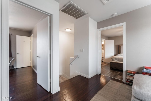 corridor featuring an upstairs landing, visible vents, baseboards, and hardwood / wood-style floors