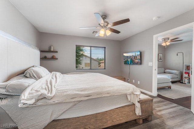 bedroom featuring visible vents, baseboards, ceiling fan, and wood finished floors