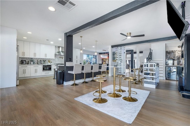 living area with beverage cooler, wood finished floors, visible vents, a toaster, and recessed lighting