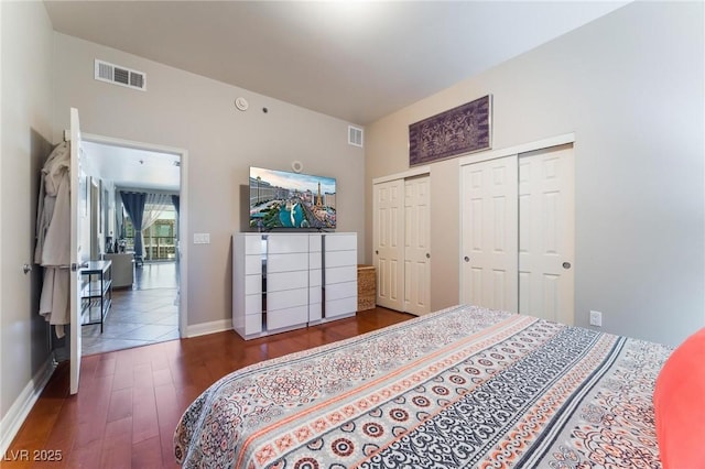 bedroom with visible vents, dark wood-type flooring, two closets, and baseboards