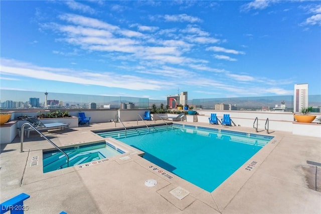 community pool with a view of city, a hot tub, a patio, and fence