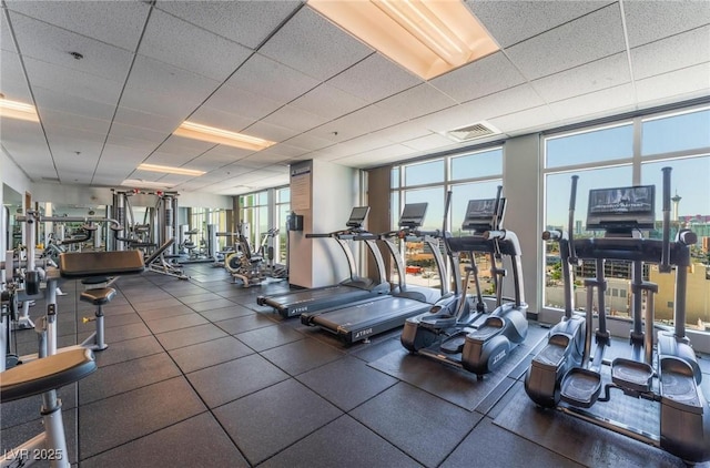 exercise room featuring a drop ceiling, floor to ceiling windows, and visible vents