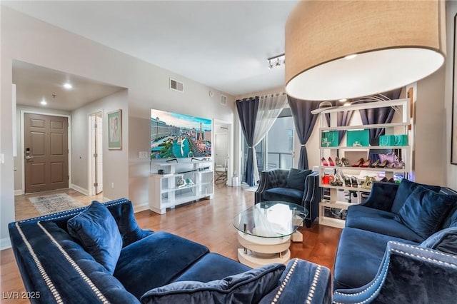 living area featuring visible vents, baseboards, and wood finished floors