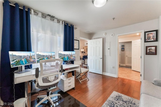 office space featuring electric panel, baseboards, and hardwood / wood-style flooring