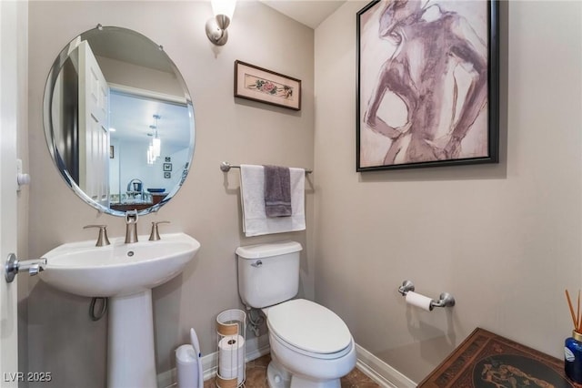 bathroom with a sink, baseboards, and toilet