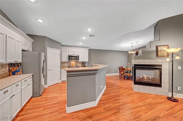 kitchen featuring light wood-type flooring, stainless steel appliances, decorative backsplash, and a sink