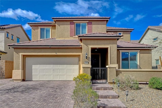 prairie-style house with fence, a tile roof, stucco siding, decorative driveway, and a garage