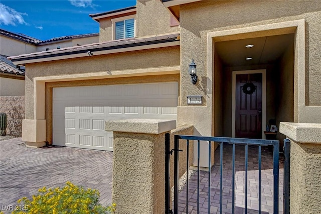 view of exterior entry with an attached garage and stucco siding