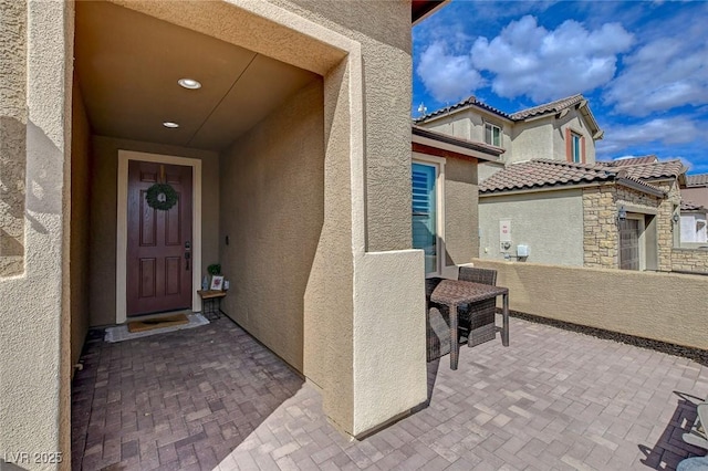 doorway to property featuring stucco siding, stone siding, and a tile roof