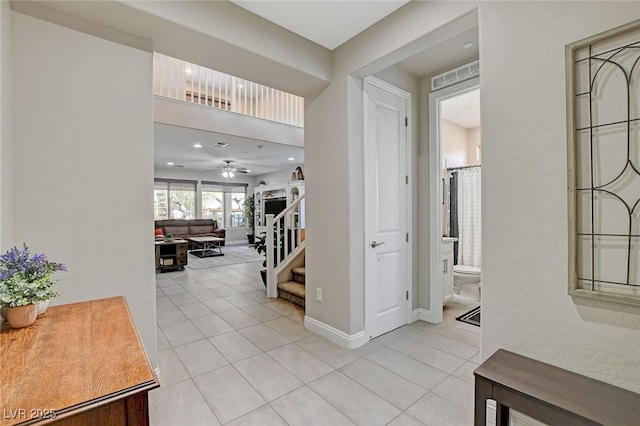 hall featuring light tile patterned flooring, visible vents, stairs, and baseboards