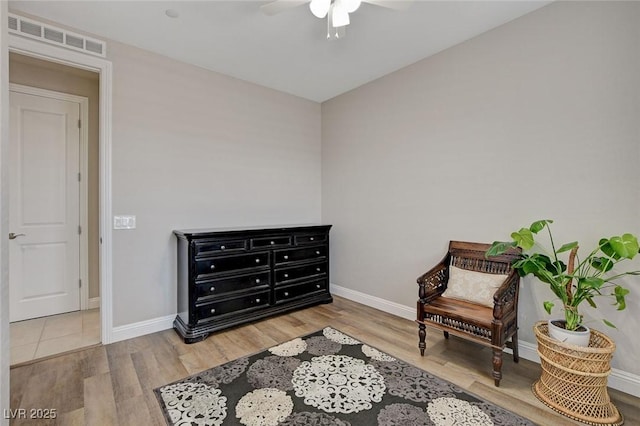 sitting room with wood finished floors, visible vents, and baseboards